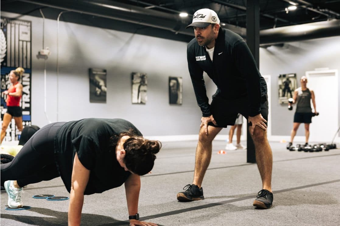 Coach Nate coaching a member through a plank during a 30-minute session at Fit Body Boot Camp Matthews